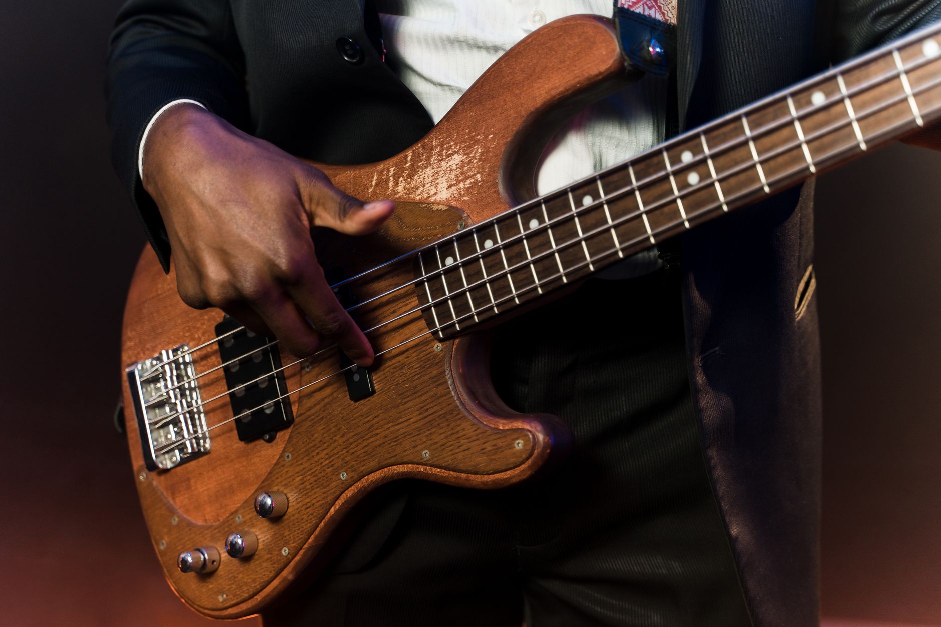 Un musicien joue de la basse électrique en bois sur scène.